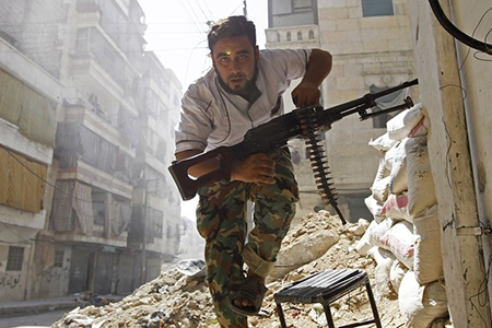 A Free Syrian Army fighter takes cover during clashes with Syrian Army in Aleppo